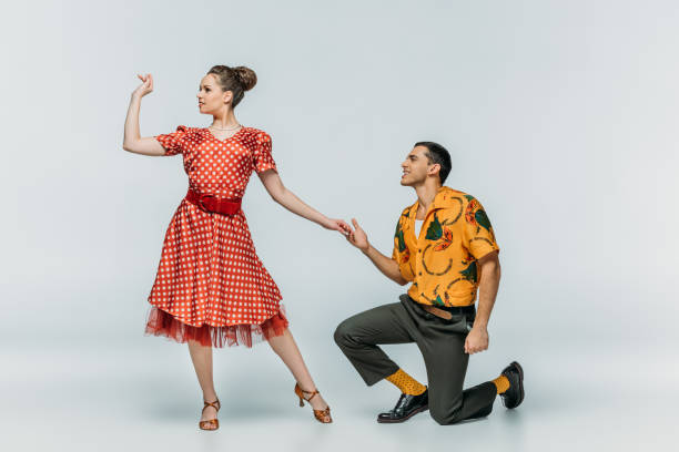 istock handsome man standing on knee and inviting pretty woman to dance boogie-woogie on grey background 1198219941