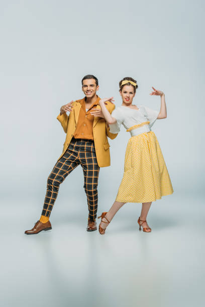 cheerful dancers looking at camera while dancing boogie-woogie on grey background cheerful dancers looking at camera while dancing boogie-woogie on grey background boogie woogie dancing stock pictures, royalty-free photos & images