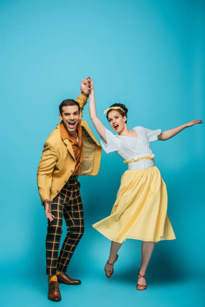 happy dancers holding hands while dancing boogie-woogie on blue background happy dancers holding hands while dancing boogie-woogie on blue background boogie woogie dancing stock pictures, royalty-free photos & images