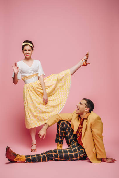 istock cheerful man sitting on floor and girl waving at camera while dancing boogie-woogie on pink background 1198219951