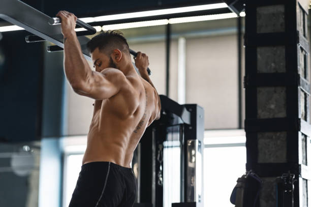 istock Muscular athlete pulling up on horizontal bar at gym 1198220056