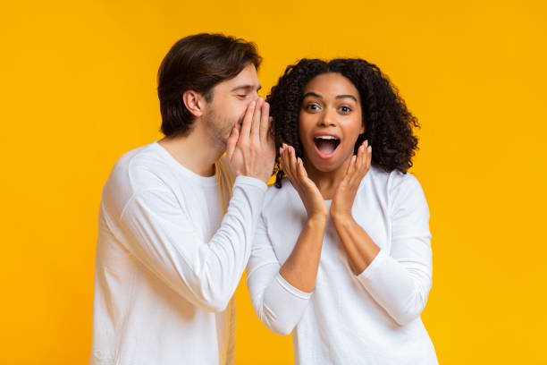 istock Young man sharing secret with his shocked black girlfriend 1198221012