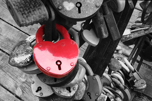 Red heart shaped padlock hangs on the bridge of lovers.  Concept - symbol of love and loyalty.