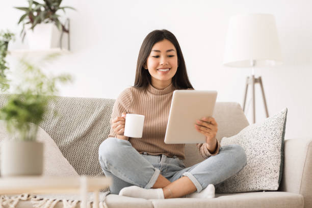 istock Cheerful girl reading e-book on digital tablet 1198221784