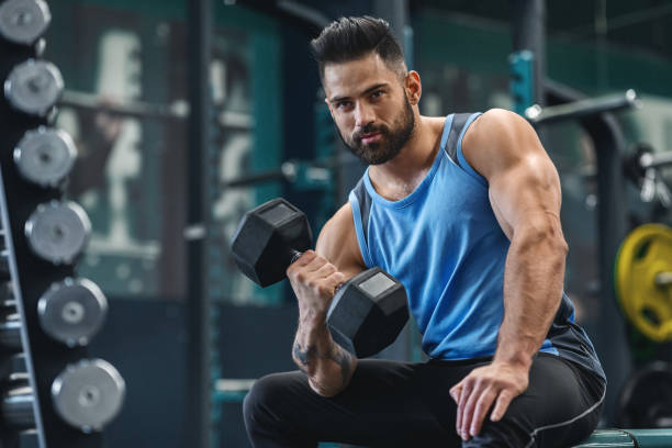 istock Handsome bodybuilder picking up dumbbells at gym 1198222382