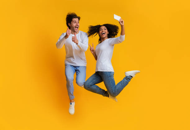 istock Joyful interracial couple taking selfie while jumping, having fun together 1198222388