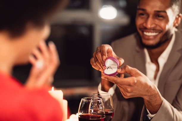 afro hombre dando anillo de compromiso de novia, cita romántica en el restaurante - young women wedding married engagement ring fotografías e imágenes de stock