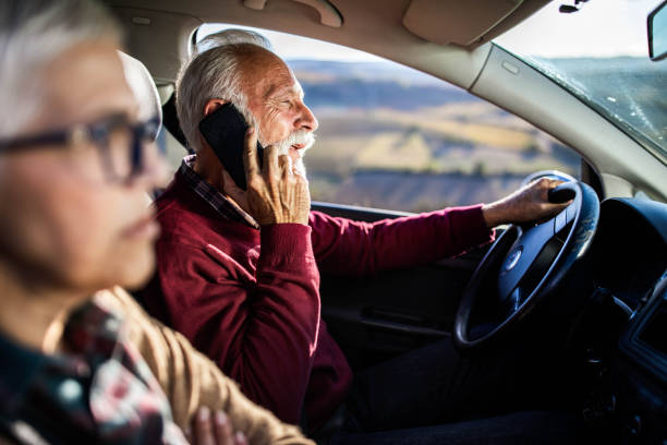 istock Careless senior man talking on cell phone while going on a trip with his wife by car. 1198223932