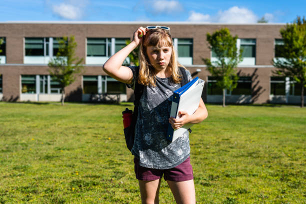istock Depressed/Sad Student standing in front of High School while holding binders. 1198225250