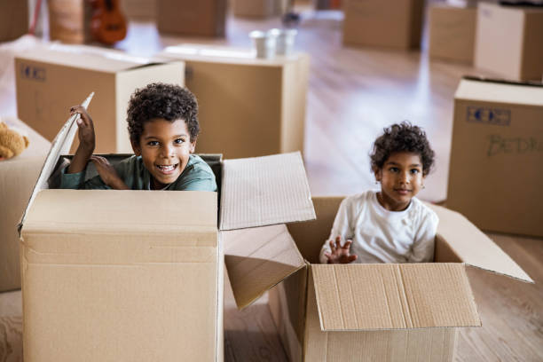 istock Happy black kids having fun inside of cardboard boxes at home. 1198225263
