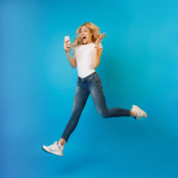 istock Wow! Excited woman jumping and using phone 1198225451