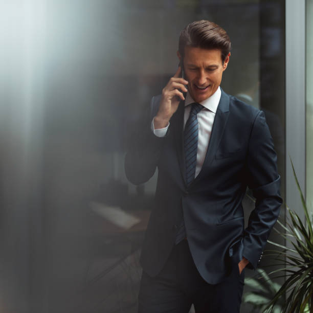 German businessman Formally dressed 55-year-old businessman is standing in the bright office and talking by mobile phone. georgijevic frankfurt stock pictures, royalty-free photos & images