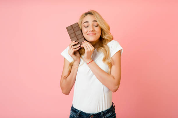 Pretty millennial woman hugging chocolate bar, pink background Pretty millennial woman hugging chocolate bar, want to eat sweets, pink background hot chocolate photos stock pictures, royalty-free photos & images