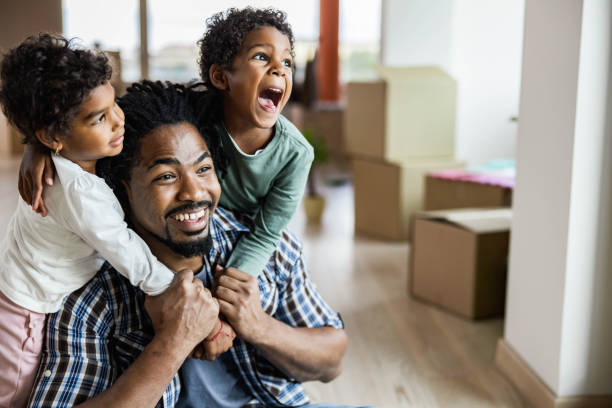 istock Loving black kids embracing their single father while moving into new home. 1198225788