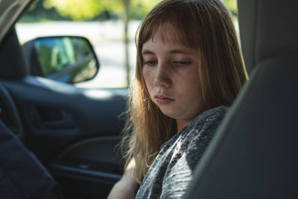 Sad/Depressed teen girl sitting in a car/suv while being driven to/picked up from school. stock photo