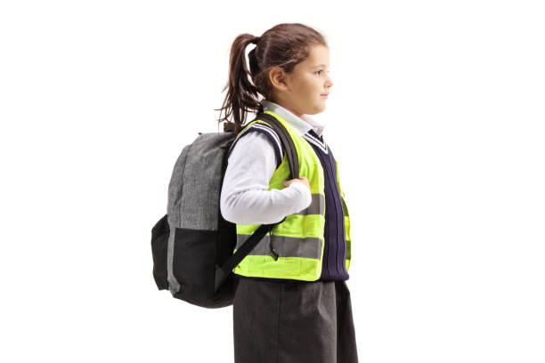 Schoolgirl with a backpack wearing safety vest isolated on white background