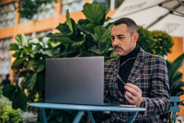 istock Businessman using laptop in sidewalk cafe 1198227216