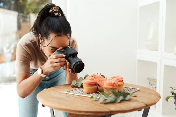 Getting close enough to capture the details Cropped shot of an attractive young businesswoman using her camera to photograph cupcakes for her blog influencer photos stock pictures, royalty-free photos & images