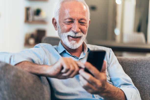 Texting Modern mature man have fun using smart phone at home one senior man only stock pictures, royalty-free photos & images