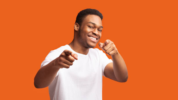 Happy black man choosing you over orange background