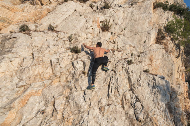 jeunes hommes torse nu musculaires grimpant la roche - mountain climbing rock climbing adventure incentive photos et images de collection