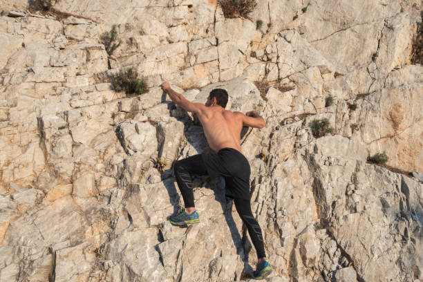 jeunes hommes torse nu musculaires grimpant la roche - mountain climbing rock climbing adventure incentive photos et images de collection