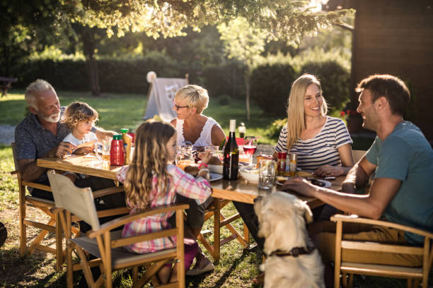 szczęśliwa dalsza rodzina korzystających w rozmowie w porze lunchu na podwórku. - dining table child grandparent grandchild zdjęcia i obrazy z banku zdjęć