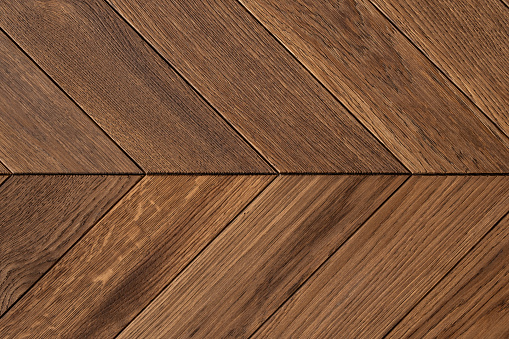 Close-up on natural and elegant hardwood floor parquet in herringbone pattern
