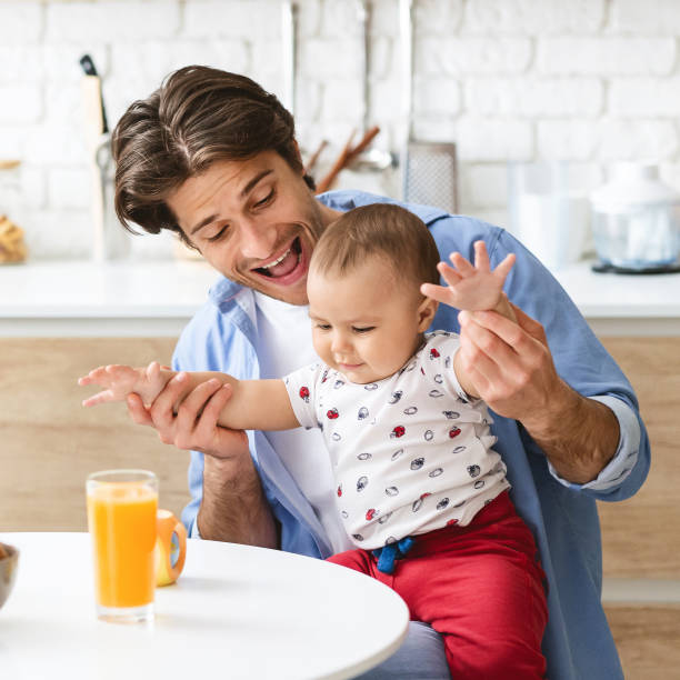 istock Cheerful daddy playing with curious baby son in kitchen 1198232207