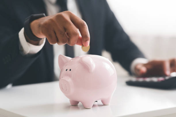 cropped of businessman putting coin into piggy bank - cheep imagens e fotografias de stock