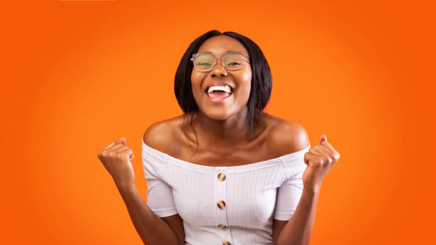 istock Lady Screaming Shaking Fists And Gesturing Yes Over Orange Background 1198232338