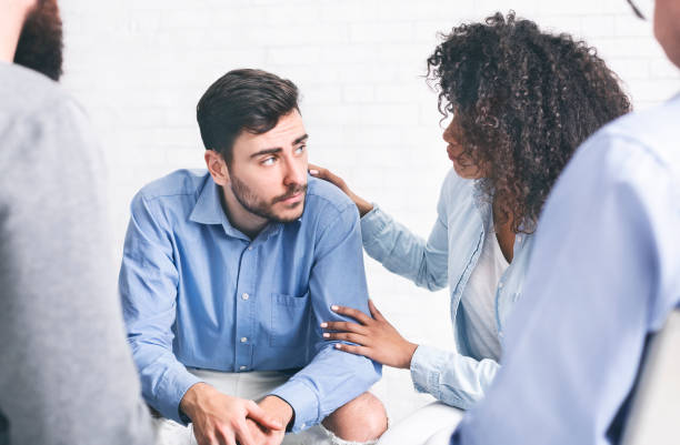 Depressed man getting support from patients of rehab group Depressed man getting some support from other patients of rehab group session alcoholics anonymous photos stock pictures, royalty-free photos & images