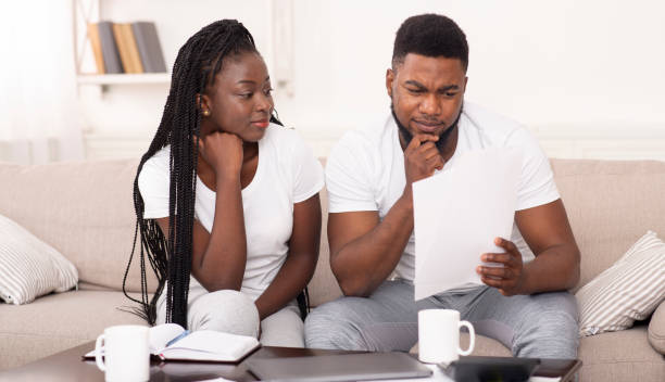 istock Black married couple reading papers sitting on couch at home 1198233449