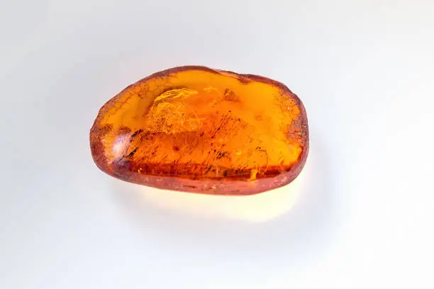 Photo of Amber stone. Mineral amber. Rosin yellow amber. Sunstone on a beach of pebbles background.