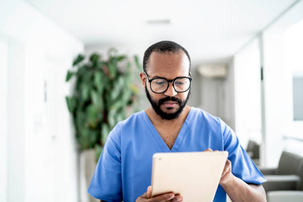 male nurse using tablet at hospital - nurse doctor scrubs male imagens e fotografias de stock