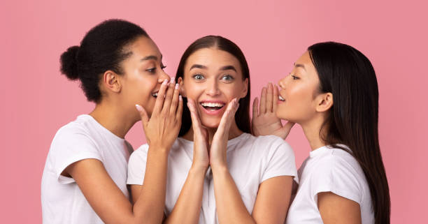 istock Three Millennial Girls Sharing Secrets Standing Over Pink Background, Panorama 1198233882