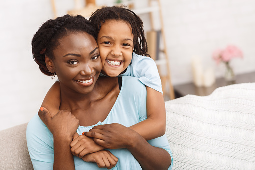 Family Bonding. Happy black mother and daughter hugging, spending time together, looking at camera, copy space