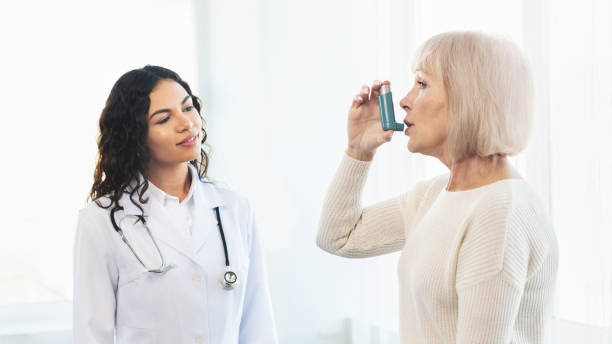 istock Physician examining mature woman using blue asthma inhaler 1198234159