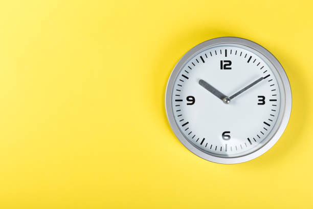 istock minimalist white wall clock with light metal on a yellow background. time concept. 1198235051