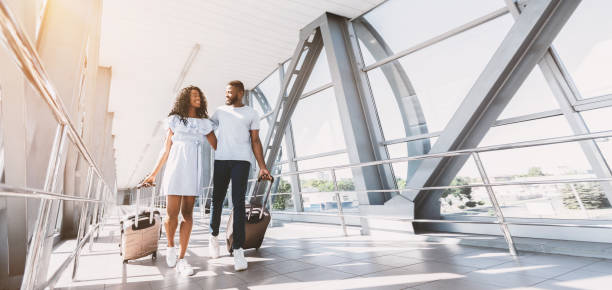 on way to honeymoon. african newlyweds walking with suitcases at airport terminal, empty space - airport passengers imagens e fotografias de stock