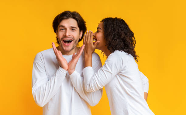 istock Interracial couple gossiping together over yellow background 1198237626