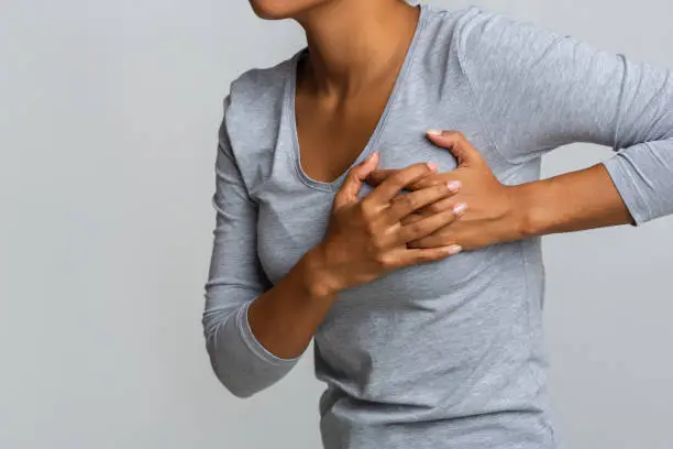 Health problem. Young african woman feeling menstrual cyclic breast pain, touching her chest, close up