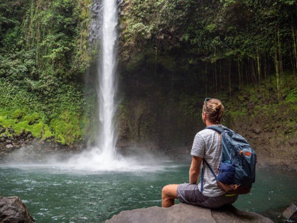 Young man contemplating waterfall in Costa Rica