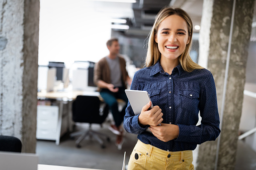 Beautiful young business woman holding tablet computer in office