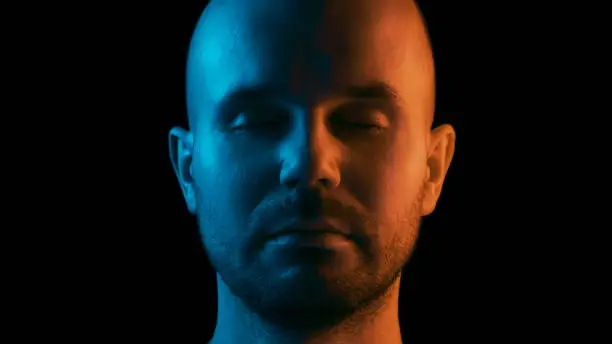 A man with closed eyes is meditating. Dual color theme. Black background.