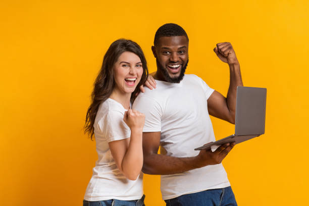 istock Overjoyed multiracial couple rejoicing success with laptop 1198244877