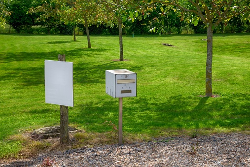 Mailbox and information blank panel in front of garden.