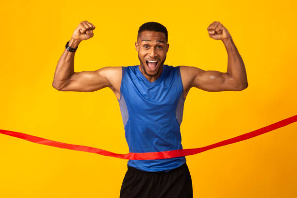szczęśliwy afro człowiek świętuje sukces łamiąc linę mety - muscular build sprinting jogging athlete zdjęcia i obrazy z banku zdjęć