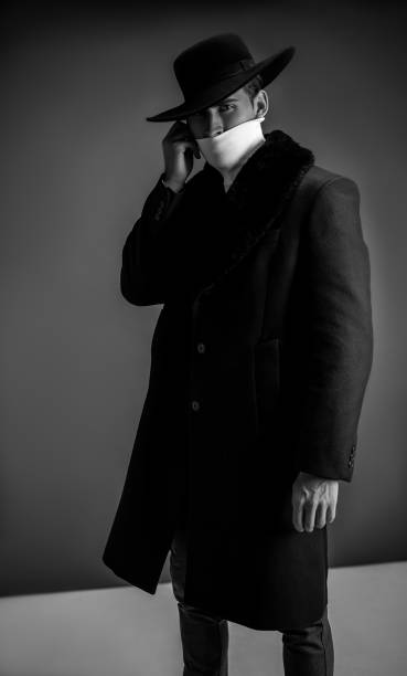 istock Fashion model posing on gray background in studio. Model tests. Man wearing in black coat, white golf and hat. 1198249951