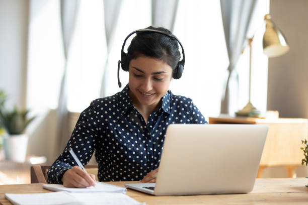 indian girl student wear headset study online teacher write notes - cyberspace support computer assistance imagens e fotografias de stock